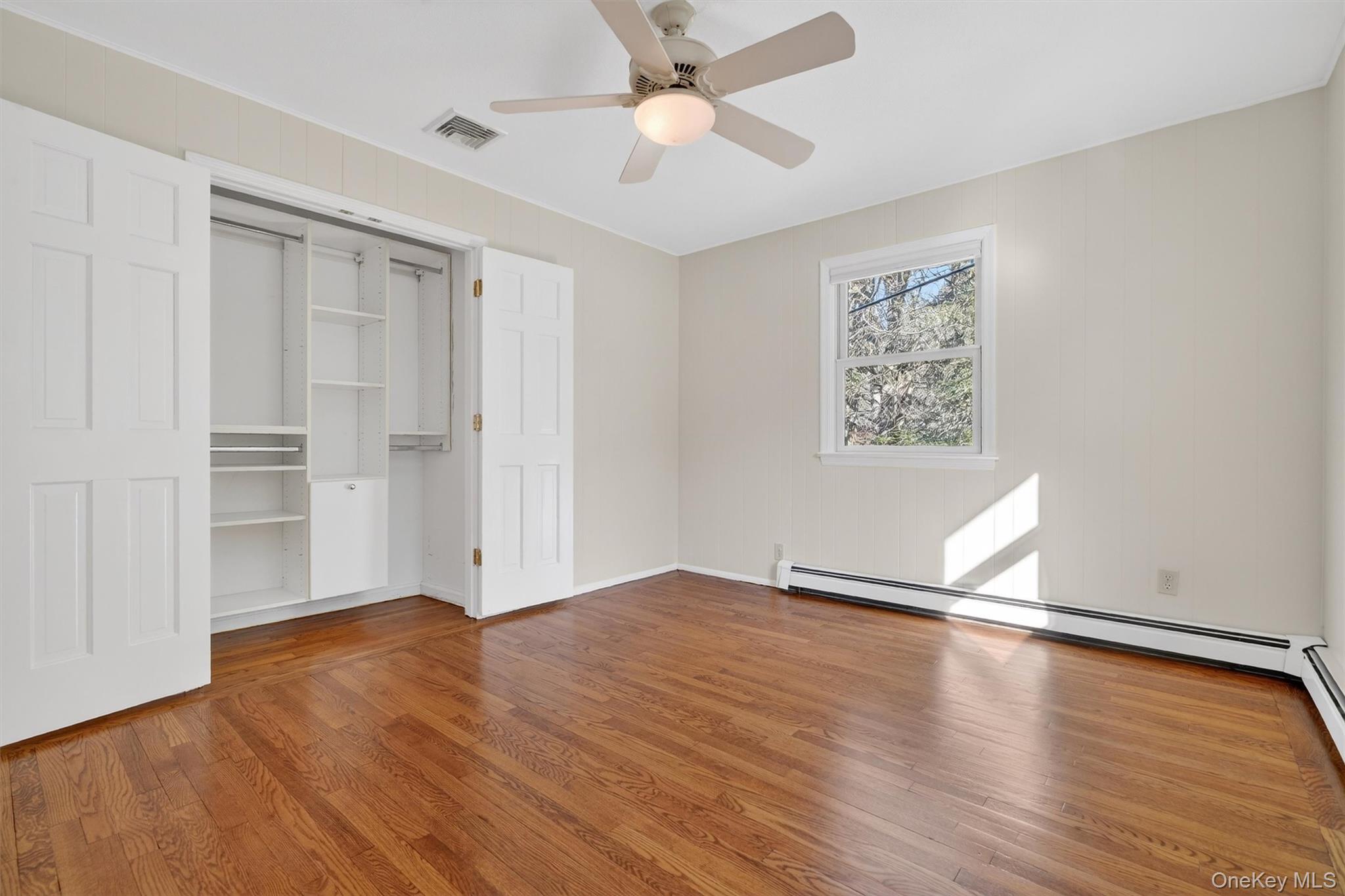 1166 Hunterbrook Road Yorktown Heights, NY 10598 - Photo 16 of 36 an empty room with wooden floor chandelier fan and windows