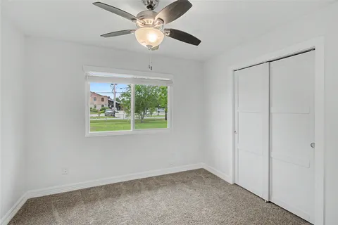 an empty room with windows and fan