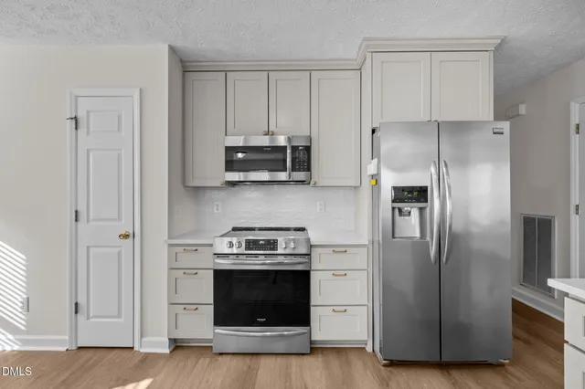 a kitchen with stainless steel appliances a stove a microwave and a hard wood floors