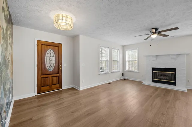 an empty room with wooden floor a ceiling fan and windows