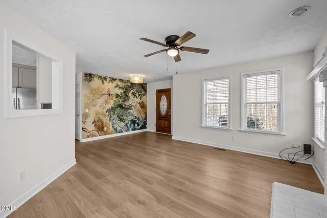 a view of an empty room with a window and wooden floor