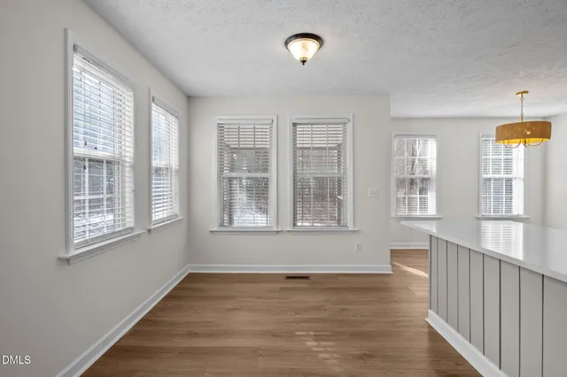 a view of an empty room with wooden floor and windows