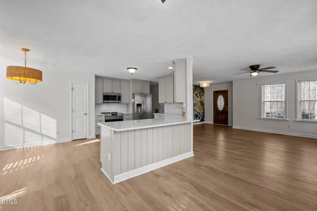 a large white kitchen with kitchen island a sink a stove and wooden floors