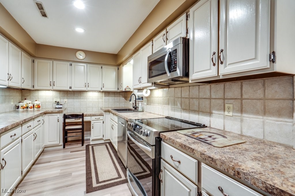 3404 South Smith Road Fairlawn, OH 44333 - Photo 3 of 37 Kitchen featuring appliances with stainless steel finishes, backsplash, white cabinets, and recessed lighting. So many cupboards. Laminate counter tops and luxury vinyl flooring.