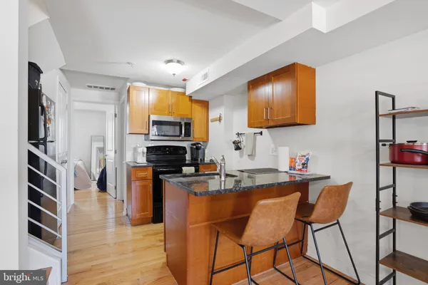 a kitchen with stainless steel appliances granite countertop a stove top oven a sink a dining table and chairs with wooden floor