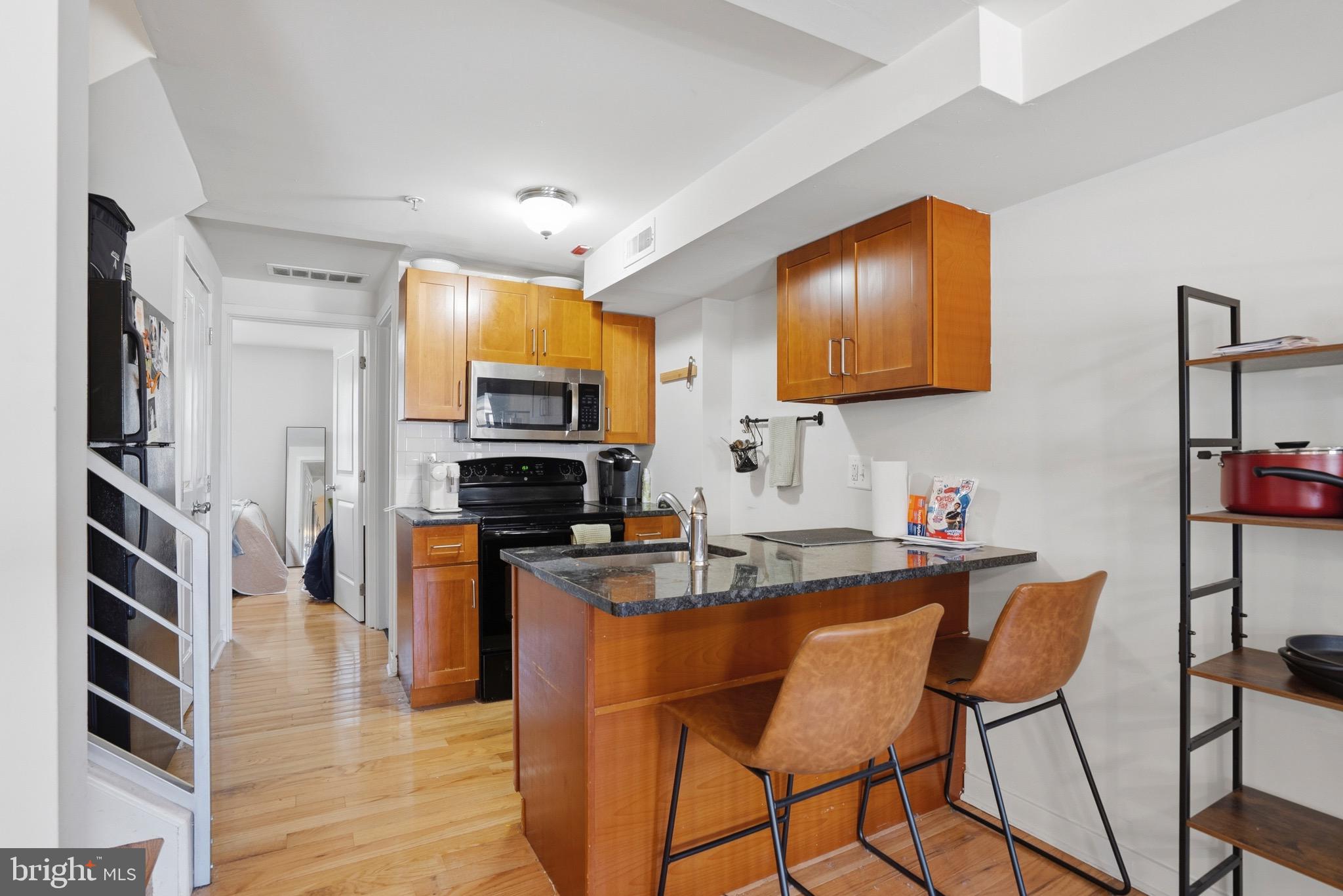 520 South 4th Street, Unit C Philadelphia, PA 19147 - Photo 5 of 18 a kitchen with stainless steel appliances granite countertop a stove top oven a sink a dining table and chairs with wooden floor