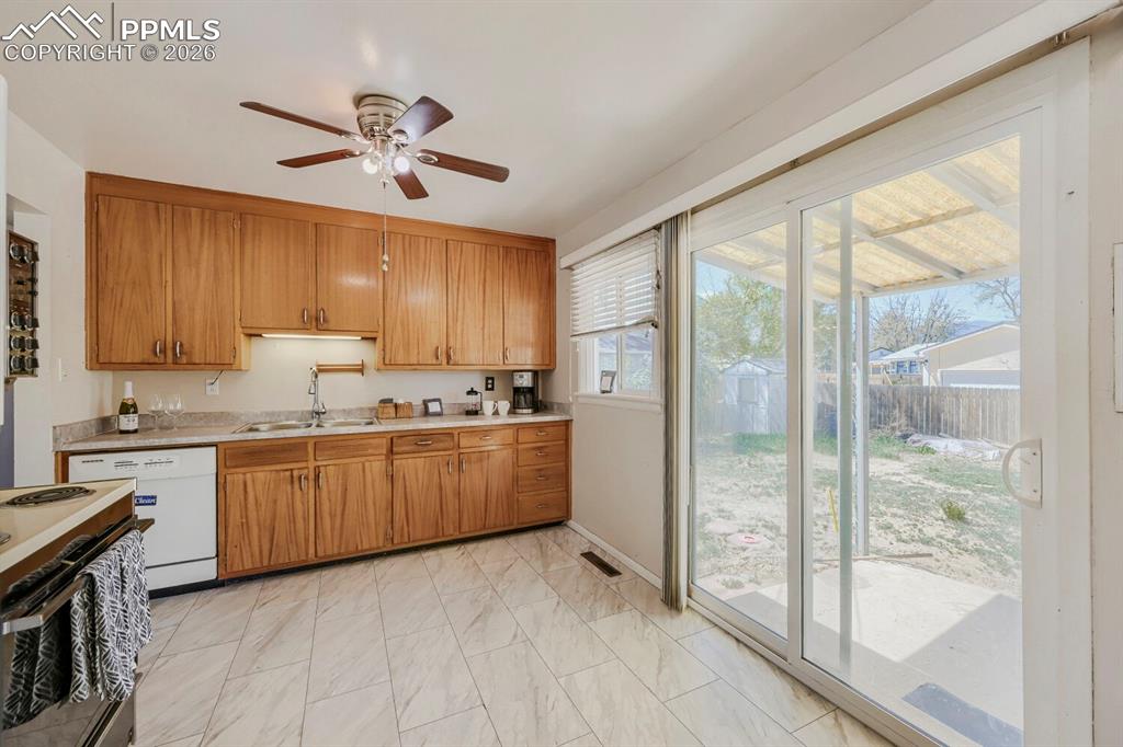 2898 Merry Lane Colorado Springs, CO 80909 - Photo 5 of 19 a kitchen with granite countertop a refrigerator a sink dishwasher a stove and a dining table with wooden floor