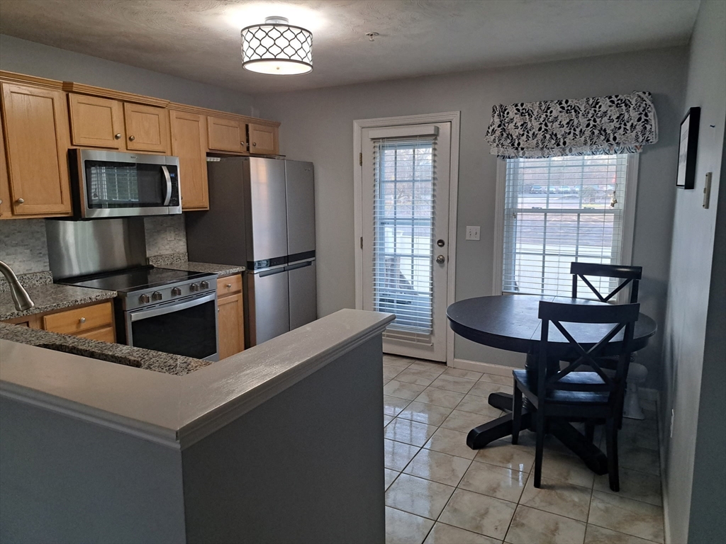 3 Boxberry Lane, Unit 3 Rockland, MA 02370 - Photo 5 of 18 a kitchen with granite countertop stainless steel appliances a table chairs microwave and sink