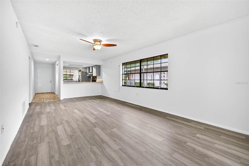 13250 Ridge Road, Unit 21 Largo, FL 33778 - Photo 19 of 36 an empty room with wooden floor chandelier fan and windows