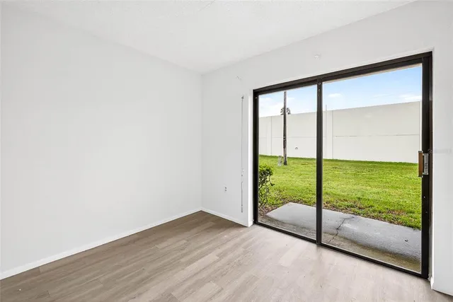 a view of an empty room with wooden floor and windows