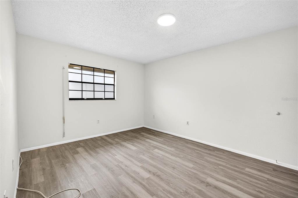 13250 Ridge Road, Unit 21 Largo, FL 33778 - Photo 23 of 36 an empty room with wooden floor and windows