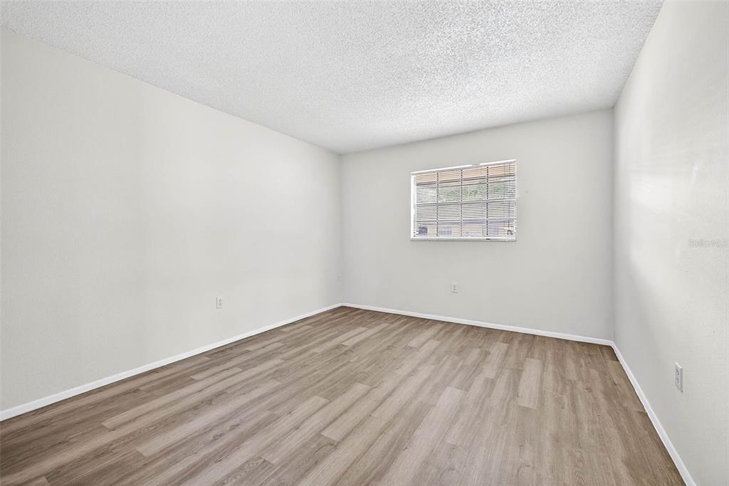 13250 Ridge Road, Unit 21 Largo, FL 33778 - Photo 25 of 36 an empty room with wooden floor and windows