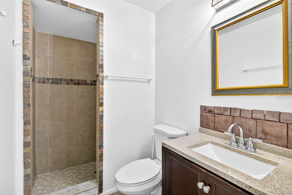 13250 Ridge Road, Unit 21 Largo, FL 33778 - Photo 7 of 36 a bathroom with a granite countertop sink toilet a mirror and shower