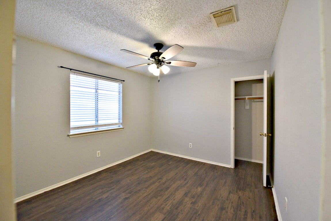 12903 Humphrey Drive Austin, TX 78729 - Photo 16 of 20 an empty room with wooden floor chandelier fan and windows