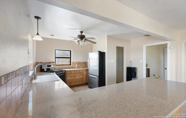 a view of a kitchen with granite countertop a refrigerator and a sink