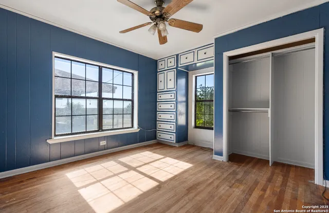a view of an empty room with a window and wooden floor