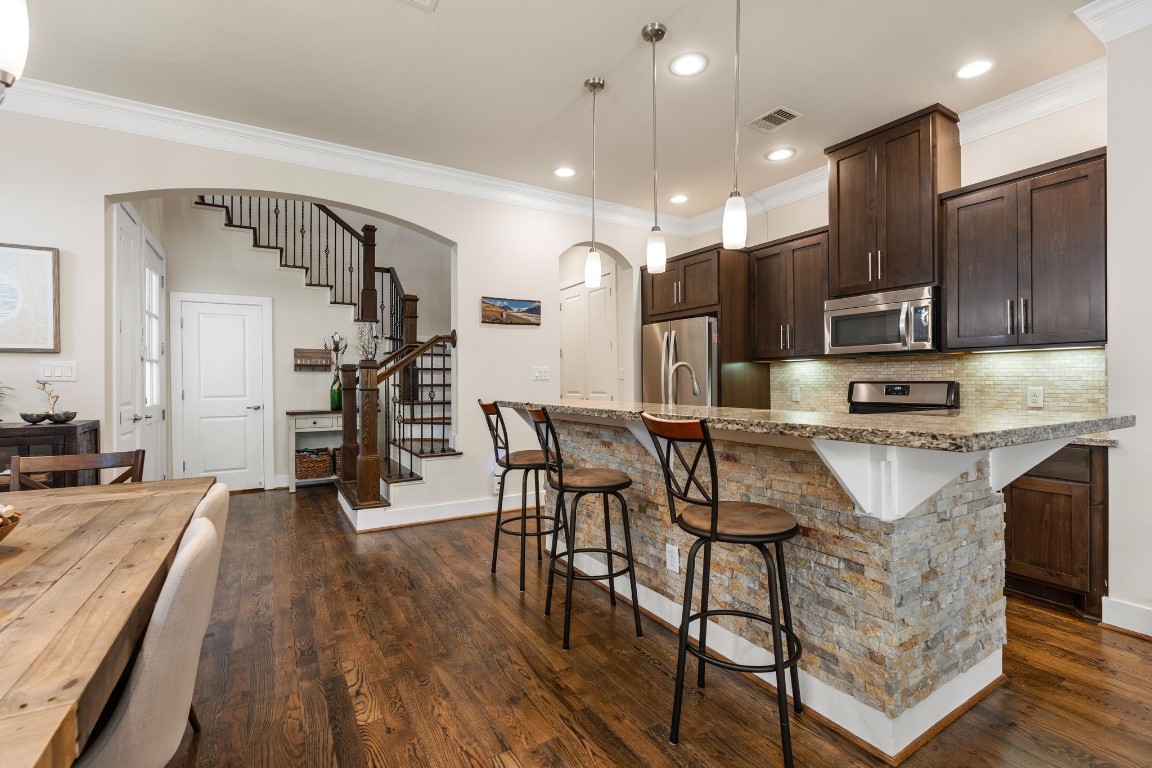 4205 Koehler Street, Unit B Houston, TX 77007 - Photo 5 of 28 a kitchen with stainless steel appliances kitchen island granite countertop a stove a refrigerator a oven a sink with island and chairs in it