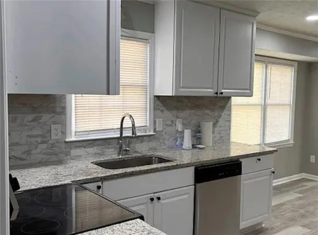 a kitchen with granite countertop a sink window and cabinets