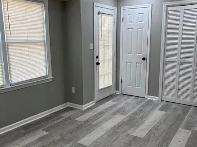 a view of an empty room with wooden floor and a window