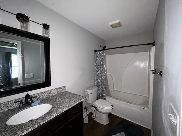 a bathroom with a granite countertop sink toilet and shower
