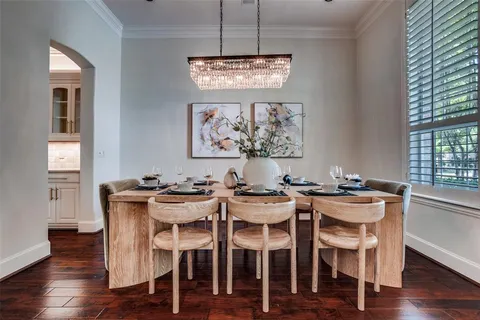 a dining room with wooden floor a chandelier a wooden table and chairs