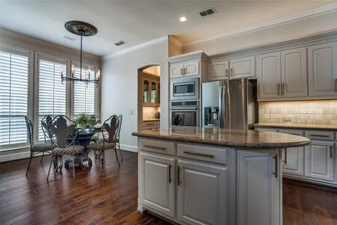 a kitchen with stainless steel appliances granite countertop a stove a refrigerator a dining table and chairs with wooden floor