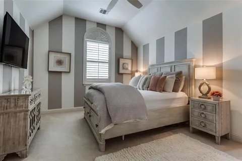 a bedroom with a bed and flat tv screen on the dresser