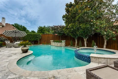 a view of a backyard with table and chairs potted plants and a large tree