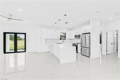 a view of kitchen with stainless steel appliances refrigerator oven and white cabinets