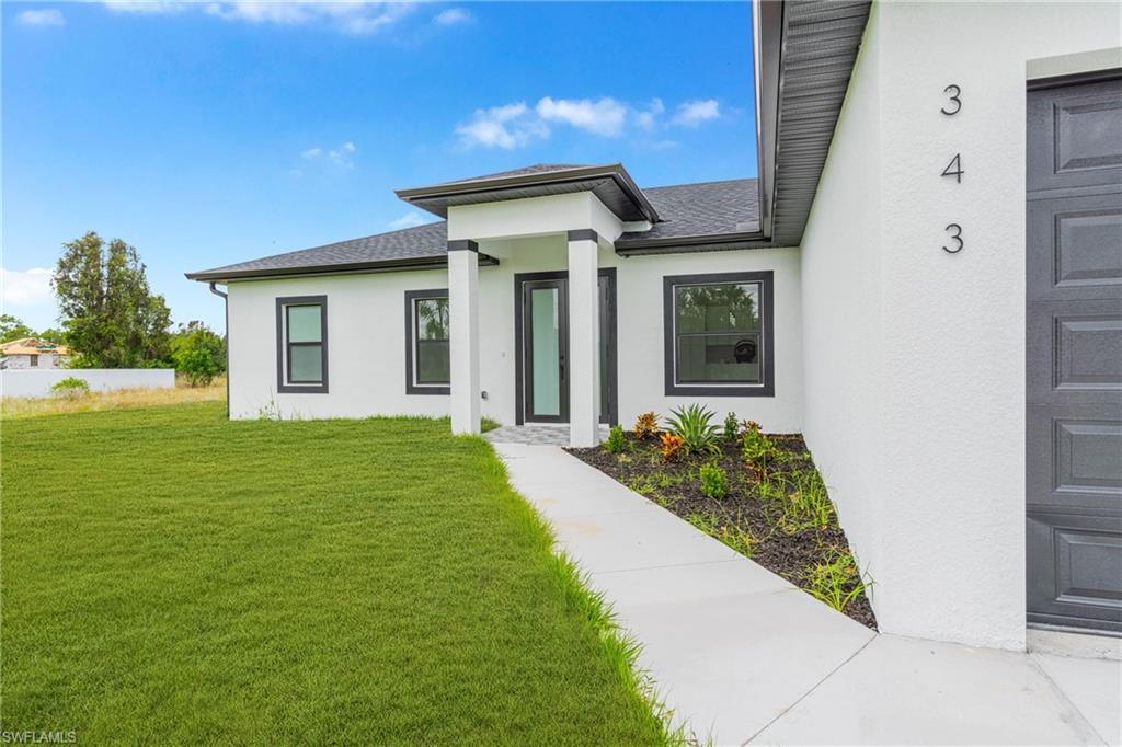 343 Pullman Street Lehigh Acres, FL 33974 - Photo 3 of 43 a front view of a house with garden