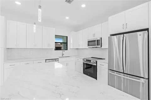 a kitchen with granite countertop white cabinets and stainless steel appliances