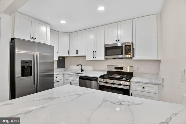 a kitchen with granite countertop a refrigerator stove and microwave