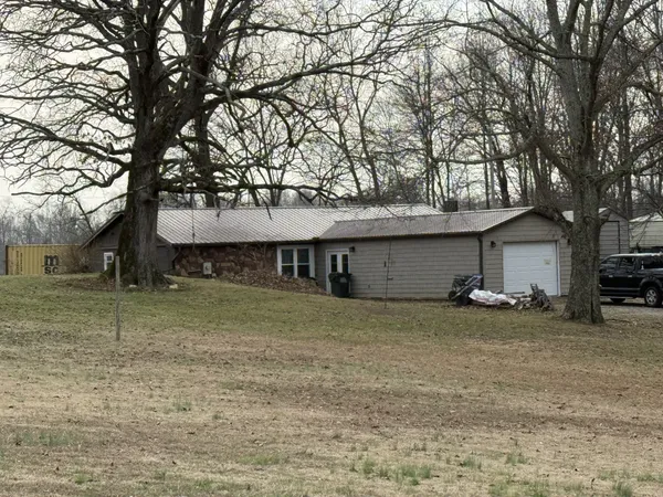 a view of a house with a large tree and a car parked in front of it