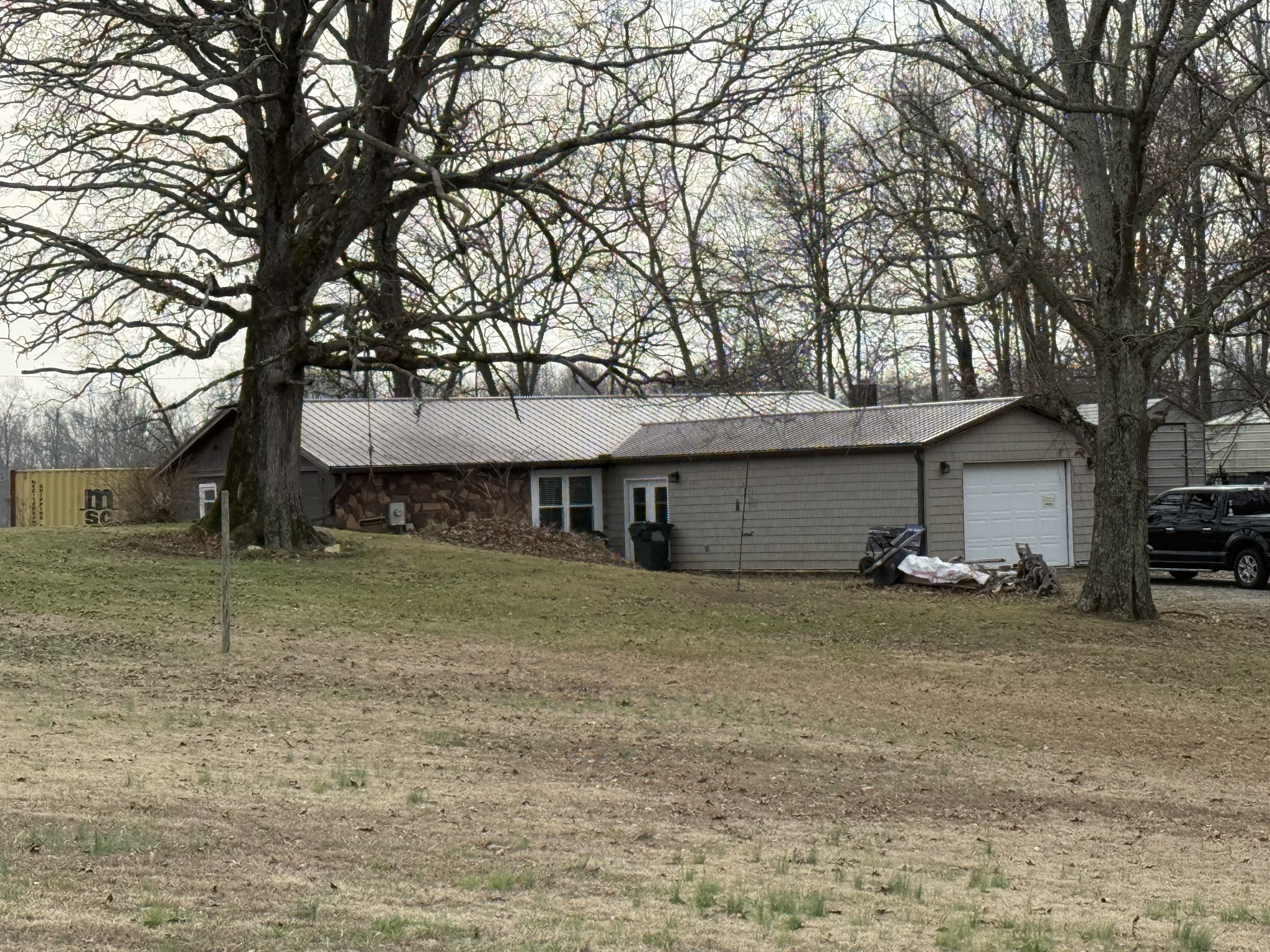 a view of a house with a large tree and a car parked in front of it