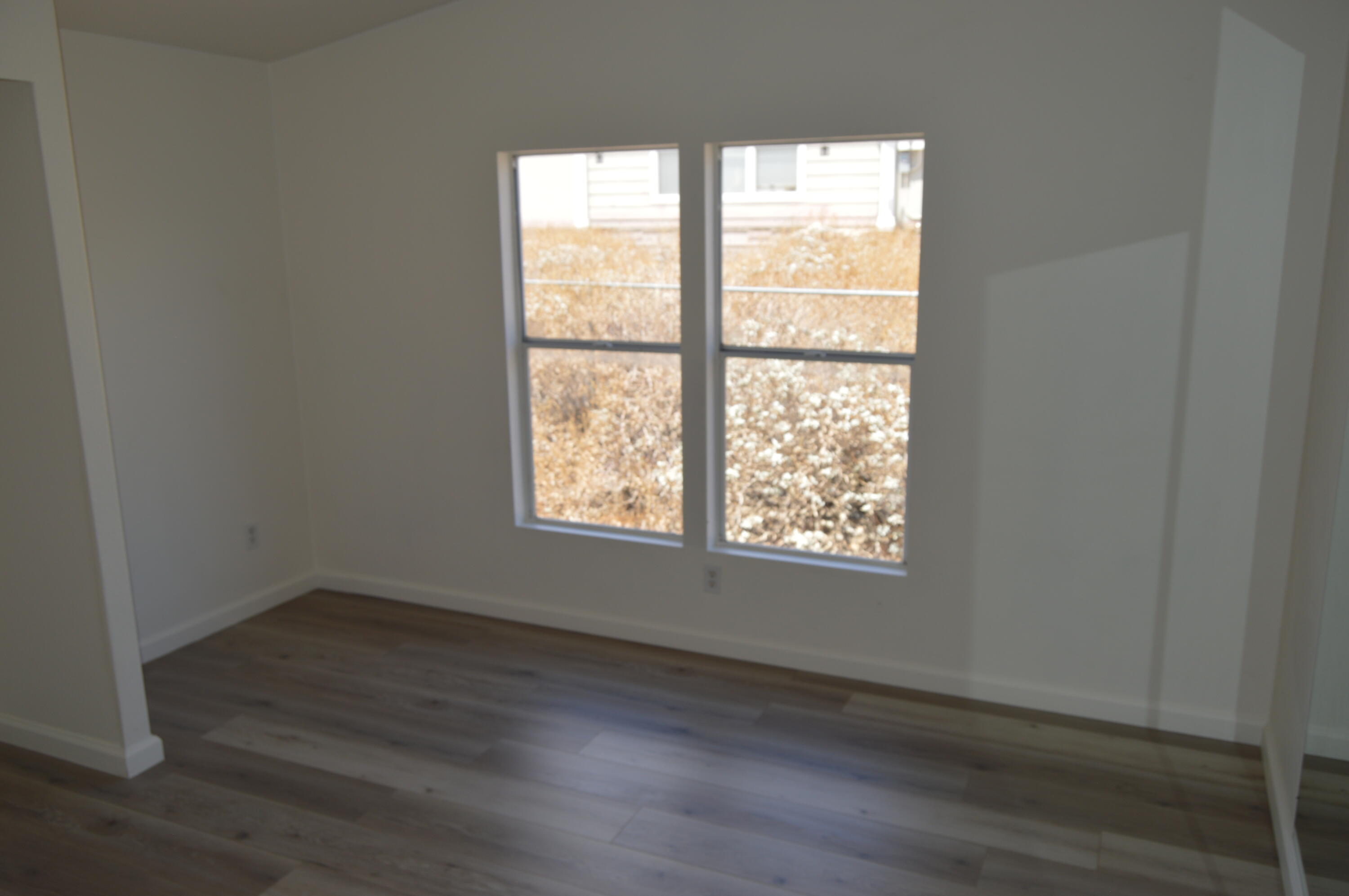 13139 Zane Way Whitewater, CA 92282 - Photo 9 of 12 an empty room with wooden floor and windows