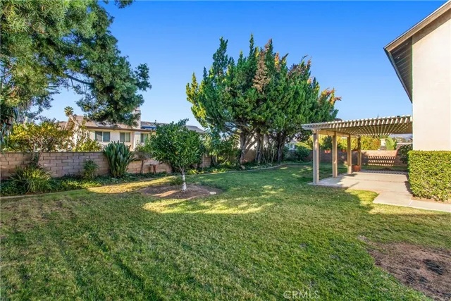 a view of a patio with table and chairs under an umbrella with large trees