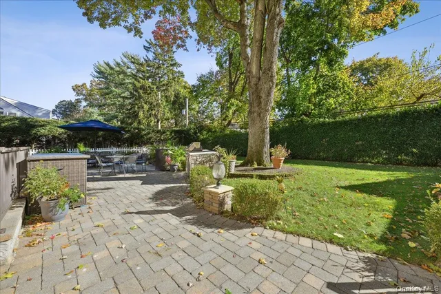 a view of a patio with table and chairs potted plants and large tree