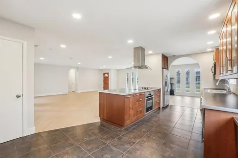 a large kitchen with stainless steel appliances a large counter top and a stove