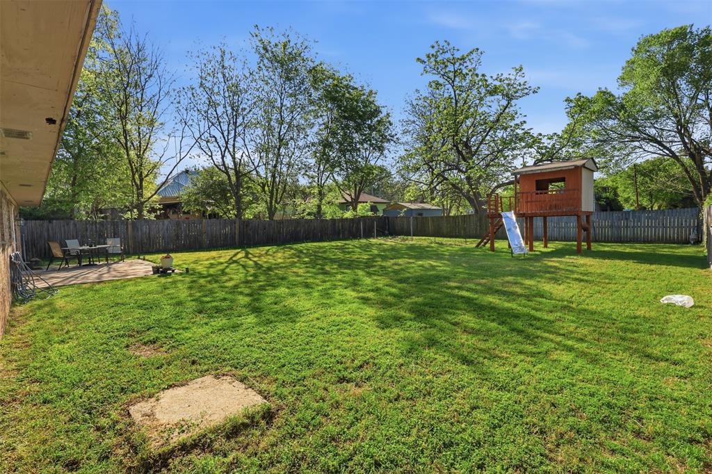 1803 Sycamore Street Commerce, TX 75428 - Photo 16 of 18 a backyard of a house with lots of green space