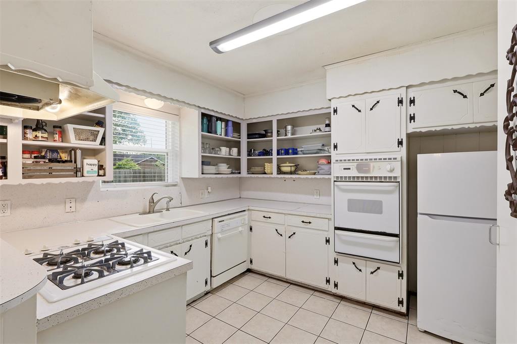1803 Sycamore Street Commerce, TX 75428 - Photo 5 of 18 a kitchen with white cabinets and white appliances