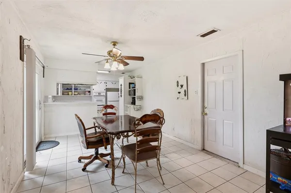 a dining room with furniture and a chandelier fan
