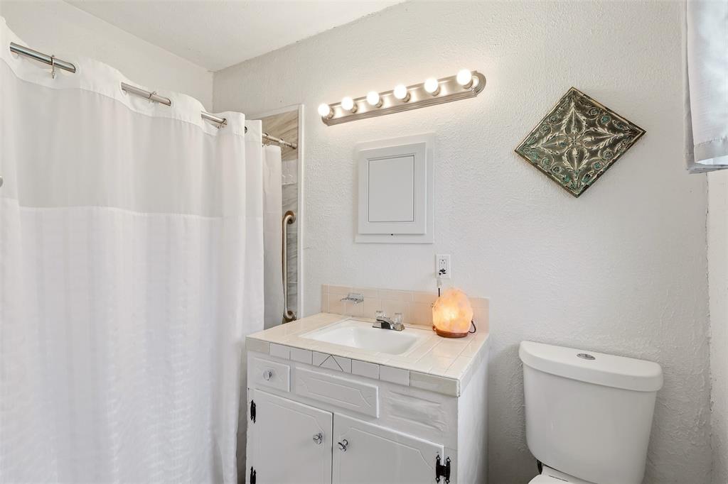 1803 Sycamore Street Commerce, TX 75428 - Photo 9 of 18 a bathroom with a sink toilet and vanity