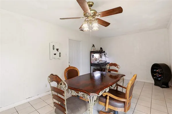 a dining room with furniture and a chandelier fan