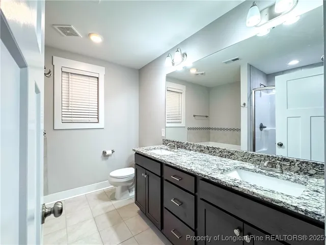 a bathroom with a granite countertop sink a toilet and a mirror