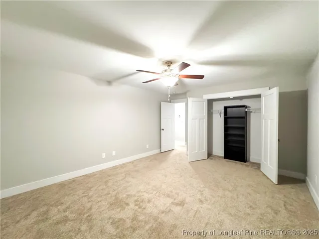 an empty room with closet and a ceiling fan