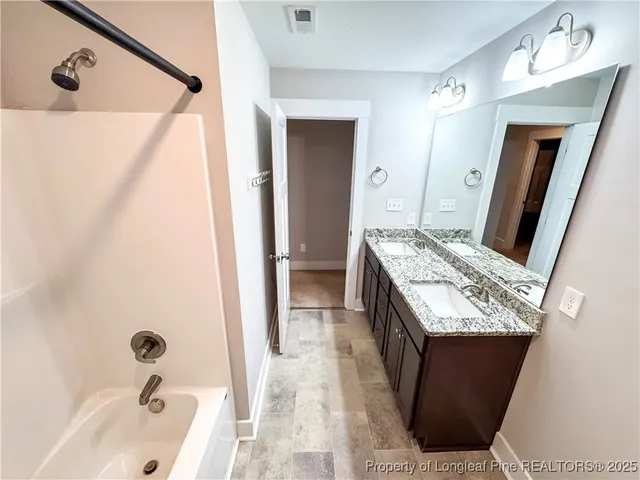 a bathroom with a granite countertop sink and mirror with bathtub