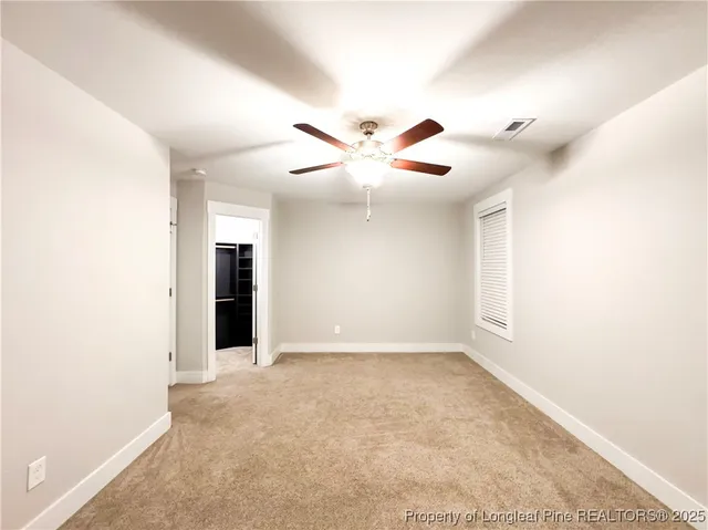 an empty room with ceiling fan and window