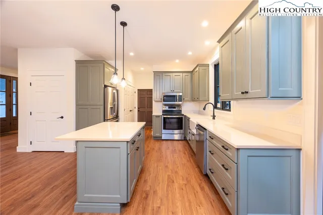 a large kitchen with stainless steel appliances a stove a sink dishwasher and a refrigerator with wooden floor