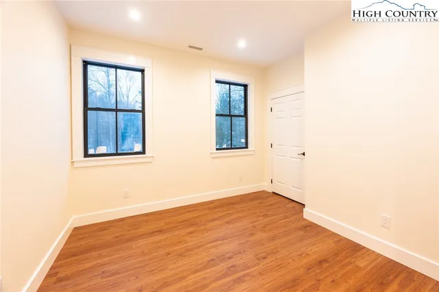an empty room with wooden floor and windows