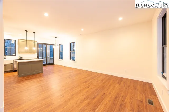 a view of a kitchen with kitchen island a sink wooden floor and a living room view